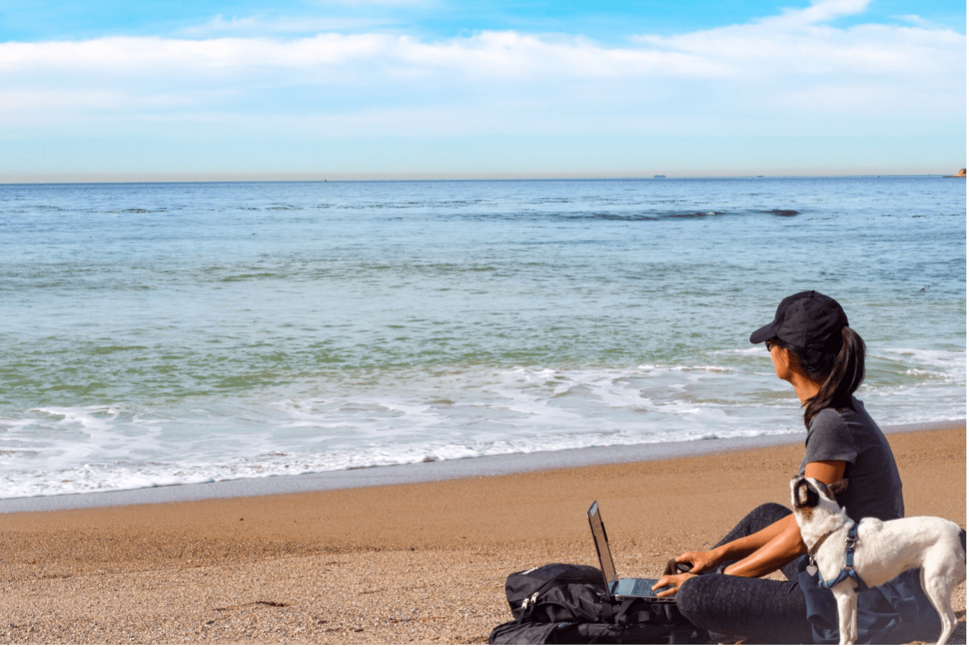 Frau mit Hund am Meer mit offenem Laptop