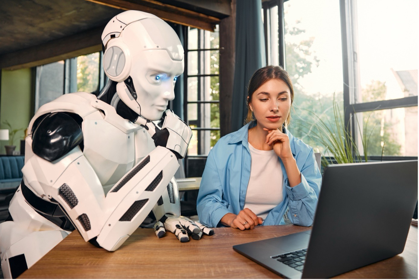 Ein Roboter und eine Frau arbeiten an einem Laptop 